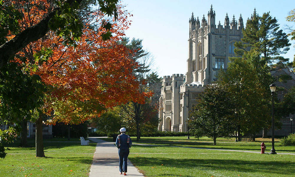 Pictured: A student walking along a path in the Quad toward the Thompson Library in Autumn